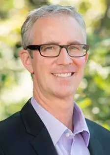Orthopedist Dr. Todd Galle smiling in rectangular glasses and a suit and tie