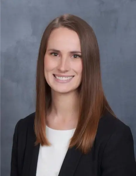Orthopedist Dr. Melinda Nicholes smiling in business attire in front of a slate background