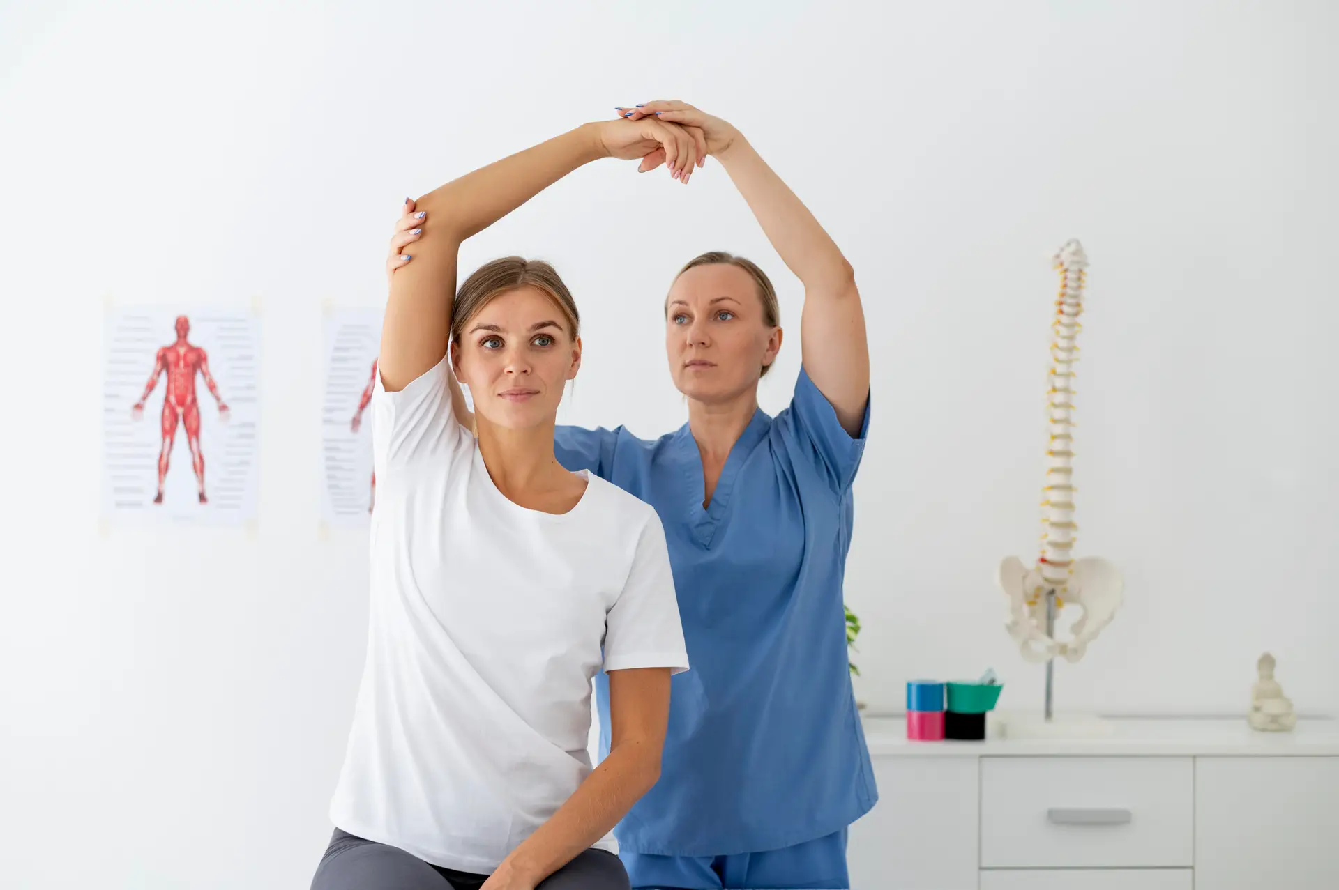 Orthopedist in blue scrubs guiding her patient in an arm and shoulder physical exam
