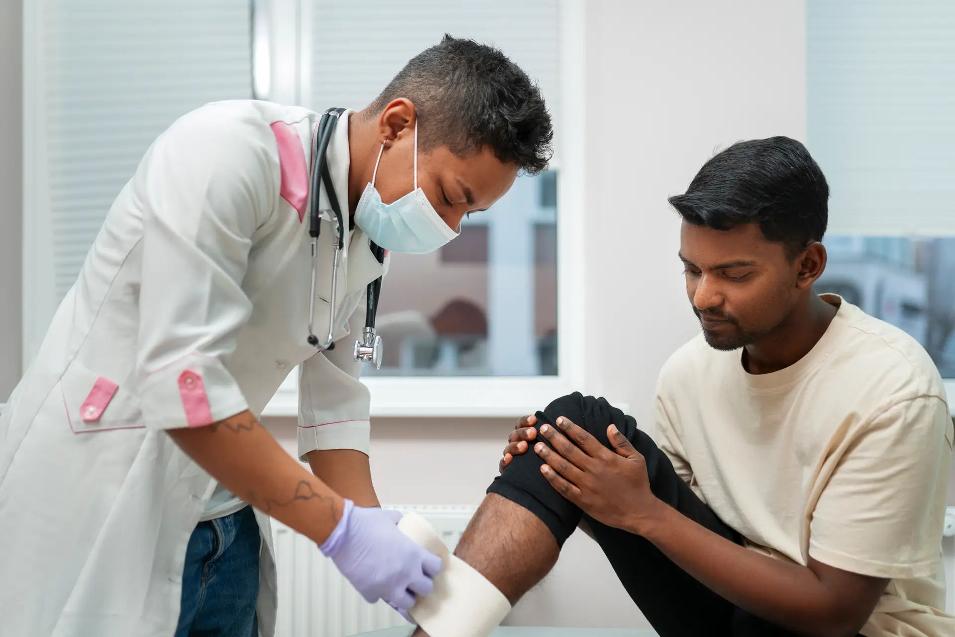 Orthopedist wrapping a bandage around the right shin of an adult patient